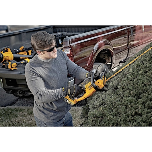 Lithium ion hedge trimmer being used by a person
