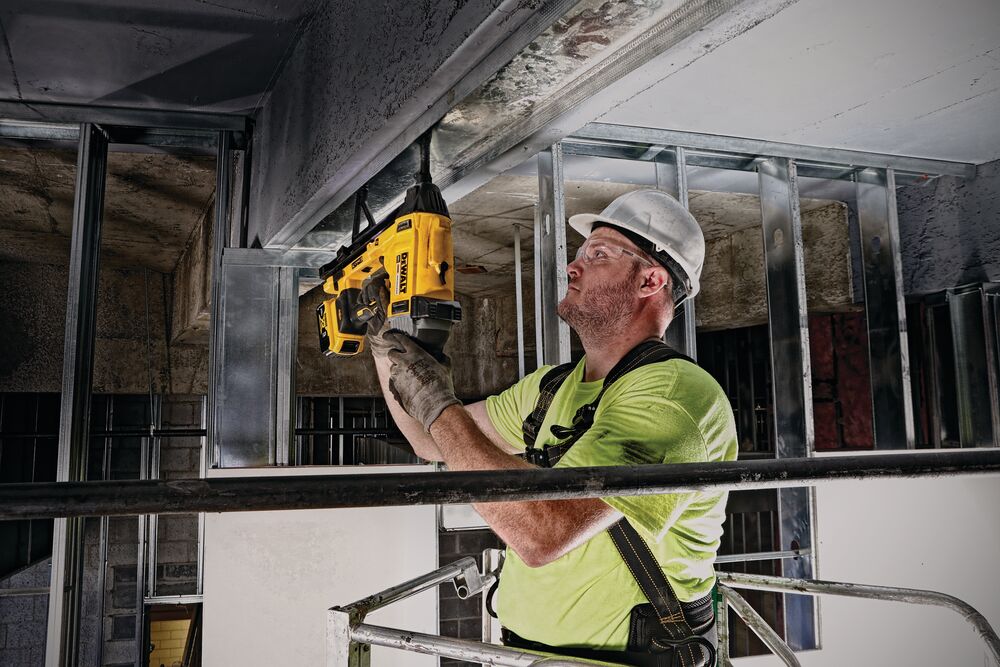 Magazine Cordless Concrete Nailer with a battery being used by a person to provide fixture to hard concrete.